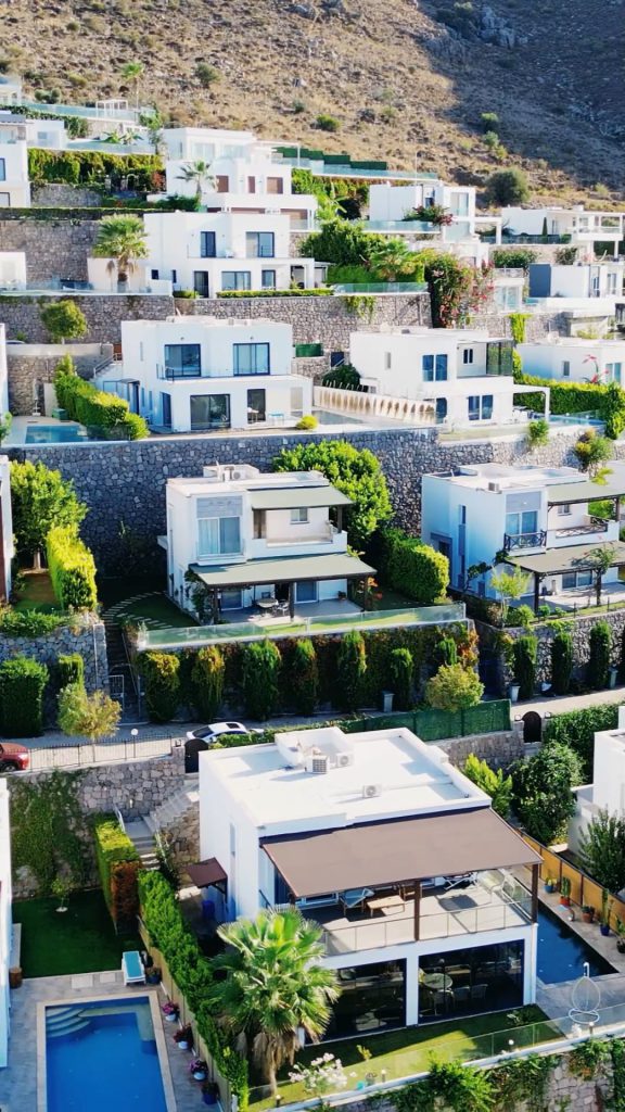 Bodrum'da yamaca kurulmuş beyaz villaların ve havuzlarının drone görüntüsü