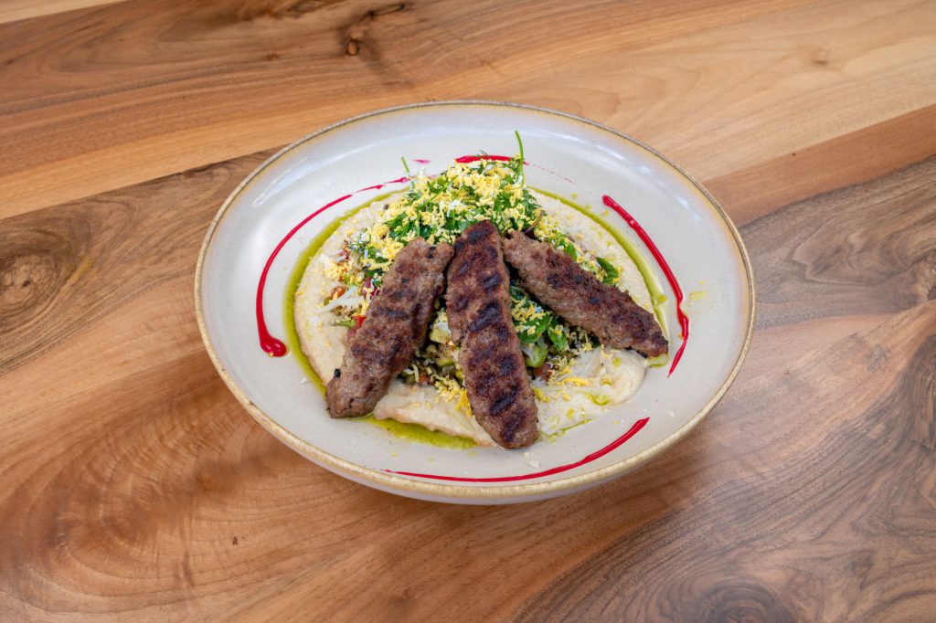 Kaf Cafe Üsküdar menü çekiminden ahşap masada kebap tabağı