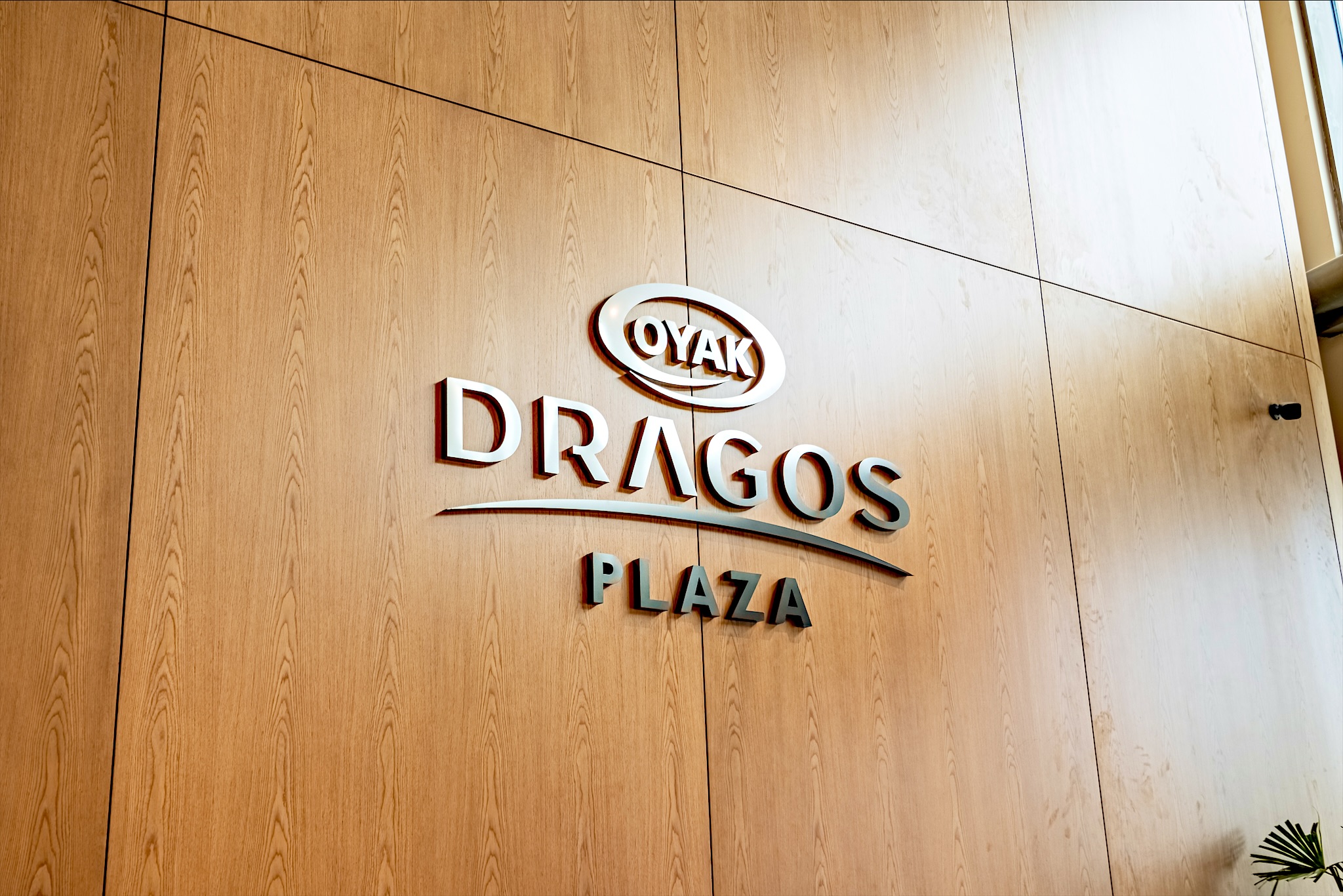 OYAK Dragos Plaza lobisinde ahşap panel üzerindeki metal logo